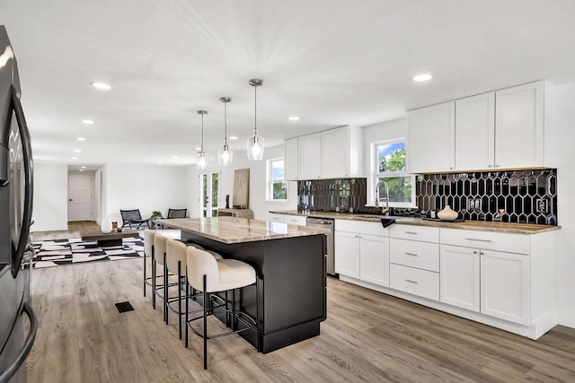 kitchen with hanging light fixtures, stainless steel appliances, a center island, and white cabinets