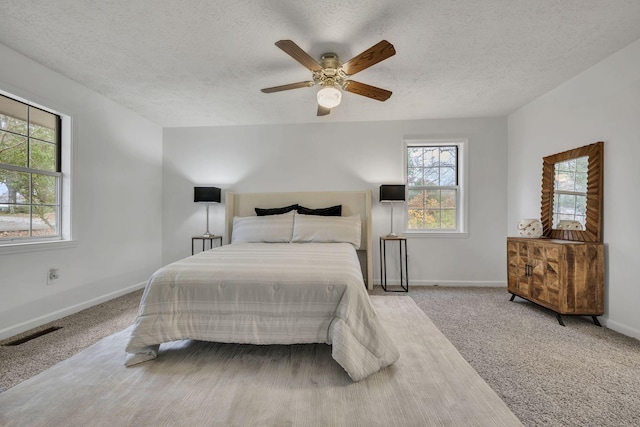 carpeted bedroom with ceiling fan and a textured ceiling