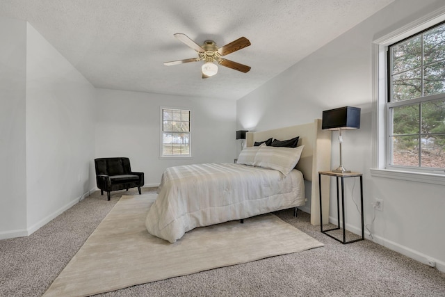 carpeted bedroom featuring ceiling fan and a textured ceiling