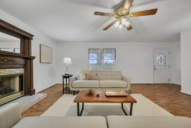 living room featuring ceiling fan, light hardwood / wood-style floors, and a textured ceiling