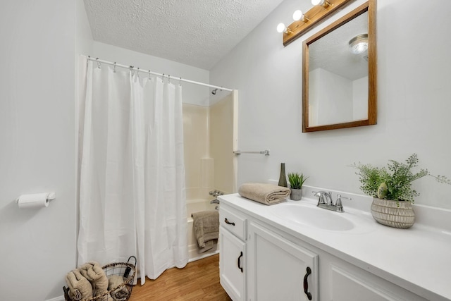 bathroom featuring hardwood / wood-style flooring, shower / tub combo with curtain, vanity, and a textured ceiling