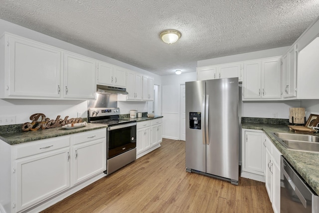 kitchen with appliances with stainless steel finishes, sink, light wood-type flooring, white cabinets, and a textured ceiling