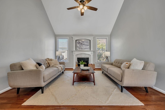 living room with hardwood / wood-style flooring, a tile fireplace, high vaulted ceiling, and ceiling fan