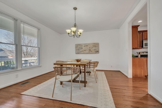 dining area featuring wood-type flooring, crown molding, and a chandelier