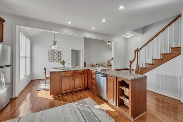 kitchen with fridge, light stone counters, light hardwood / wood-style floors, decorative light fixtures, and stainless steel dishwasher