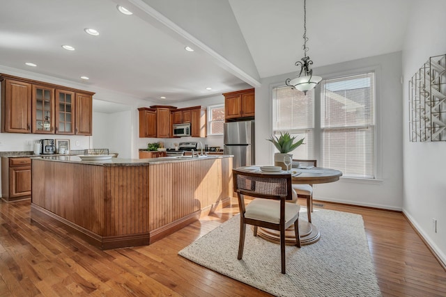 kitchen featuring a kitchen island with sink, decorative light fixtures, stainless steel appliances, and hardwood / wood-style flooring