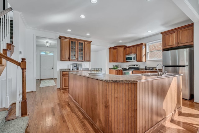 kitchen featuring sink, crown molding, a kitchen island with sink, stainless steel appliances, and light hardwood / wood-style floors