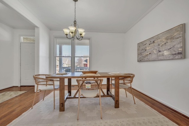 dining area featuring ornamental molding, an inviting chandelier, and light hardwood / wood-style floors