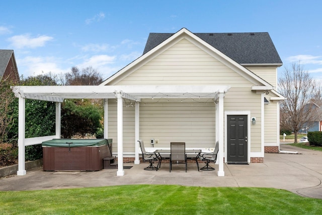 back of property with a yard, a hot tub, a pergola, and a patio