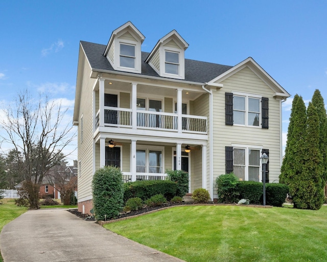 view of front of home featuring a front yard, a balcony, and covered porch