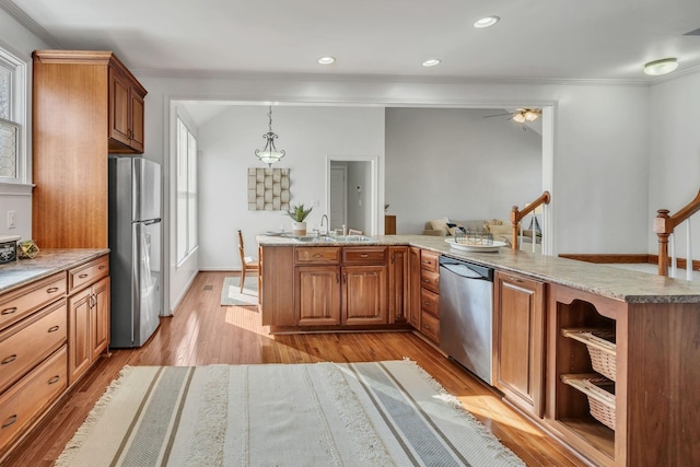 kitchen featuring ornamental molding, stainless steel appliances, hanging light fixtures, and light wood-type flooring