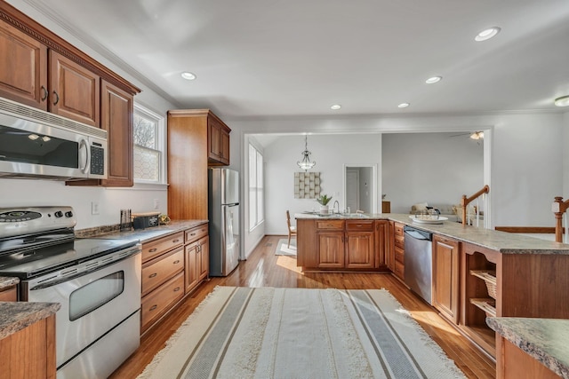 kitchen featuring sink, decorative light fixtures, appliances with stainless steel finishes, ceiling fan, and light hardwood / wood-style floors