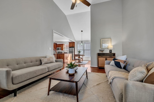 living room featuring ceiling fan, high vaulted ceiling, and light hardwood / wood-style flooring