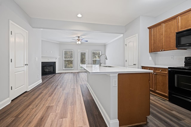 kitchen featuring an island with sink, sink, dark hardwood / wood-style floors, and black appliances