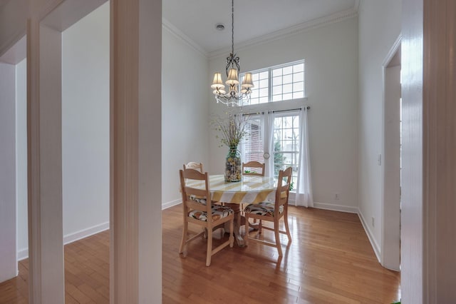 dining space featuring a notable chandelier, crown molding, light hardwood / wood-style flooring, and a high ceiling