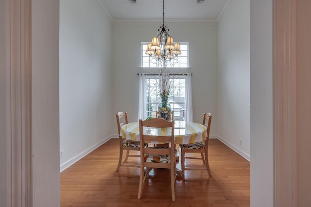 dining space with ornamental molding, hardwood / wood-style floors, and a notable chandelier