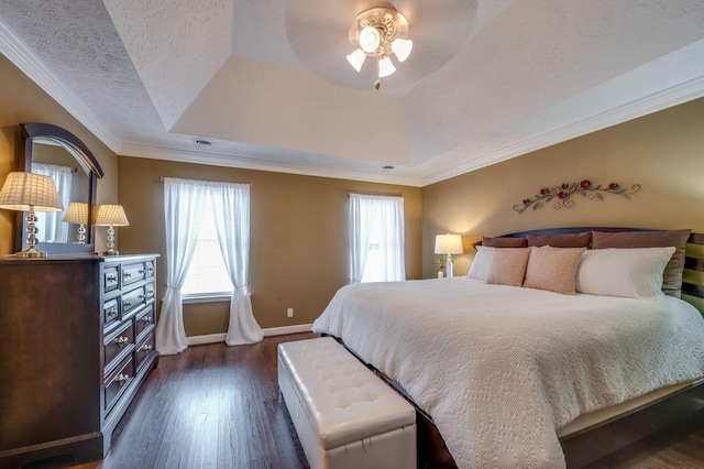 bedroom with ornamental molding, dark wood-type flooring, a textured ceiling, and a tray ceiling