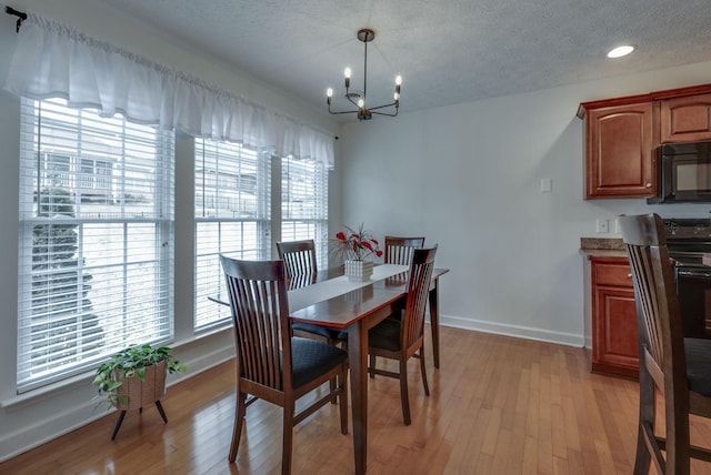 dining space with an inviting chandelier, a textured ceiling, and light hardwood / wood-style flooring