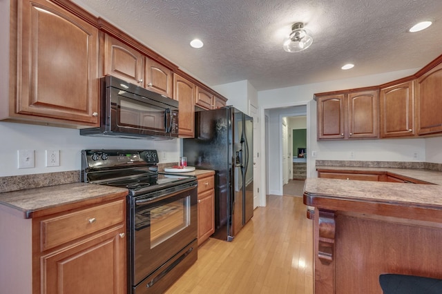 kitchen featuring light hardwood / wood-style floors, a textured ceiling, and black appliances