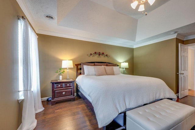 bedroom with crown molding, a textured ceiling, dark hardwood / wood-style flooring, and a tray ceiling