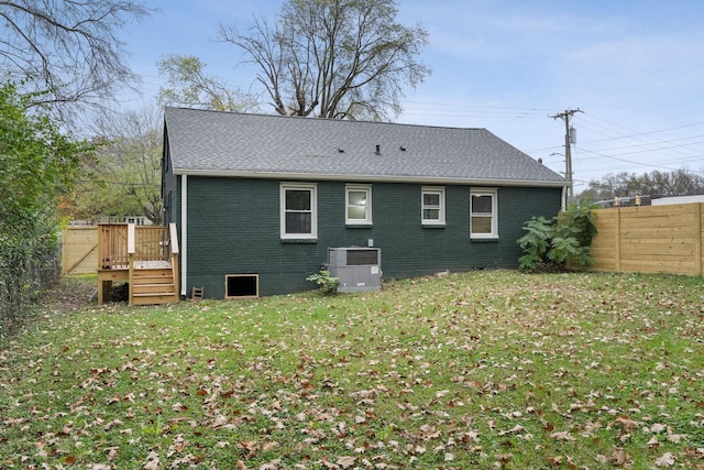 rear view of house featuring cooling unit, a deck, and a lawn