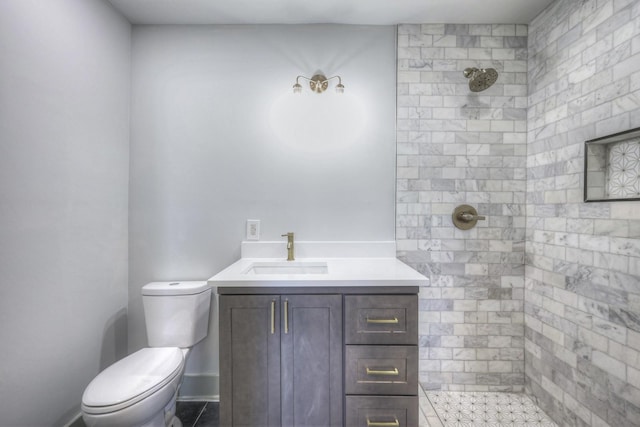 bathroom with vanity, tiled shower, and toilet