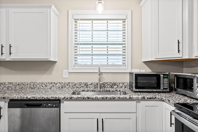 kitchen with light stone counters, sink, stainless steel appliances, and white cabinets