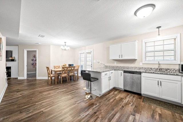 kitchen with sink, stainless steel dishwasher, kitchen peninsula, pendant lighting, and white cabinets