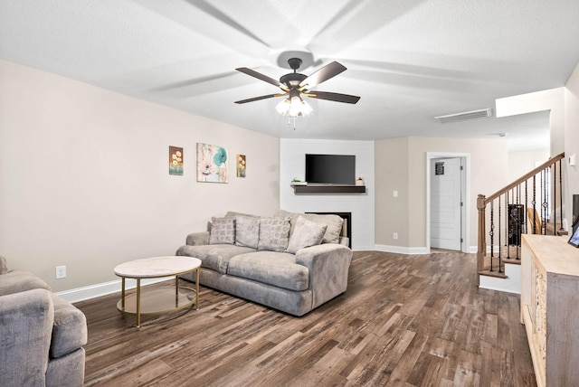 living room featuring hardwood / wood-style flooring, ceiling fan, and a textured ceiling