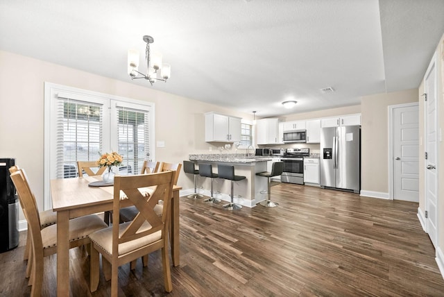 dining area with a wealth of natural light, dark hardwood / wood-style floors, and a chandelier