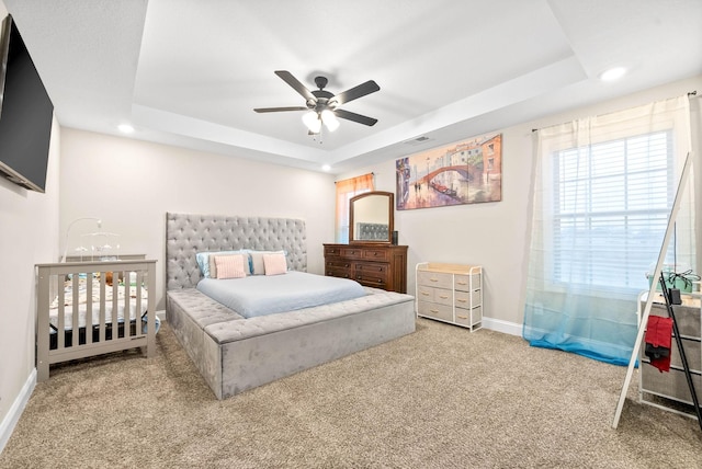 bedroom featuring light carpet, a raised ceiling, and ceiling fan