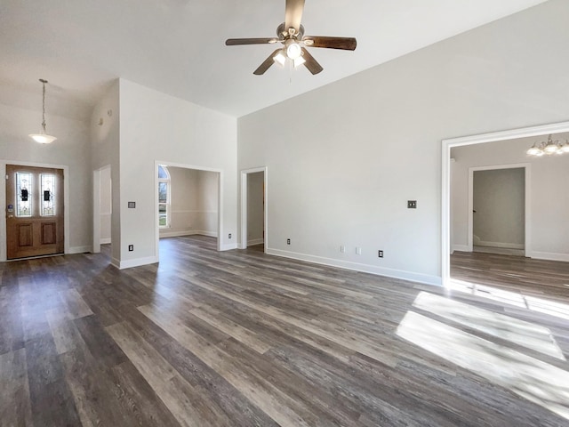 unfurnished living room featuring ceiling fan with notable chandelier, dark hardwood / wood-style floors, and high vaulted ceiling