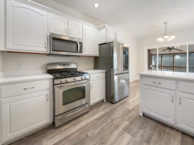 kitchen featuring appliances with stainless steel finishes, white cabinetry, hanging light fixtures, ceiling fan with notable chandelier, and light wood-type flooring