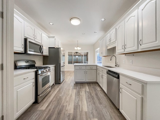 kitchen with white cabinetry, sink, hanging light fixtures, stainless steel appliances, and an inviting chandelier