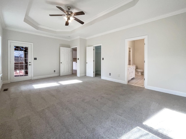 unfurnished bedroom featuring connected bathroom, crown molding, ceiling fan, a tray ceiling, and light colored carpet