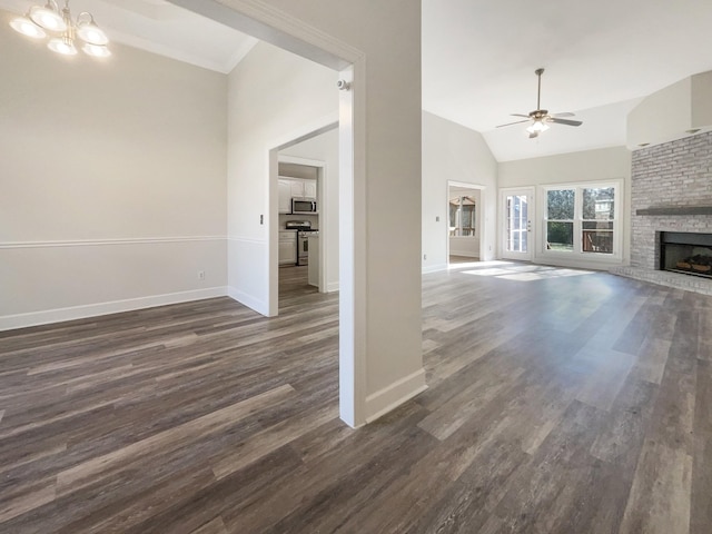 unfurnished living room featuring vaulted ceiling, dark wood-type flooring, ceiling fan with notable chandelier, and a fireplace