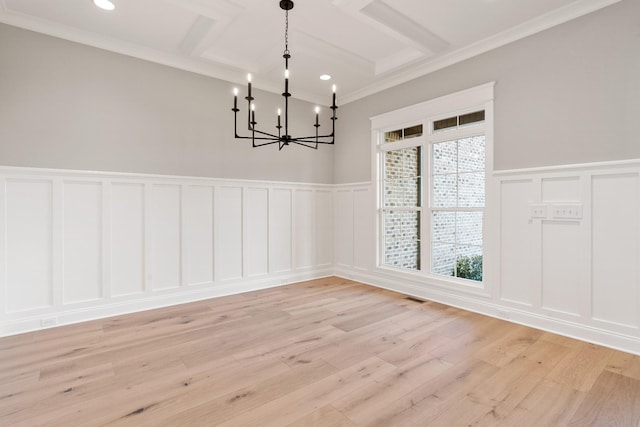 unfurnished dining area with crown molding, light wood-type flooring, and a chandelier