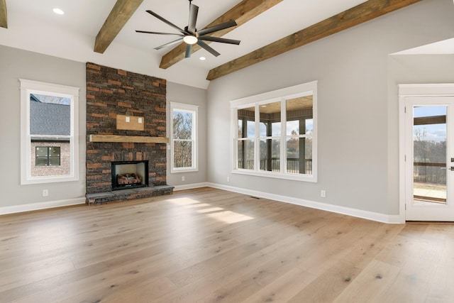 unfurnished living room with beam ceiling, ceiling fan, a stone fireplace, and light hardwood / wood-style floors