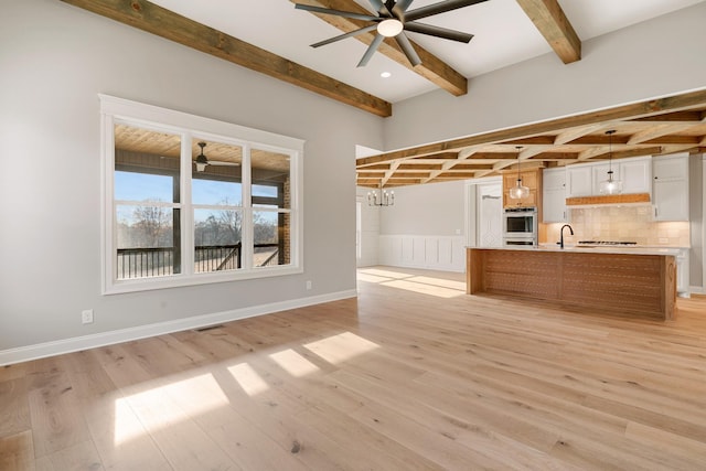 kitchen featuring pendant lighting, ceiling fan with notable chandelier, white cabinets, and light wood-type flooring