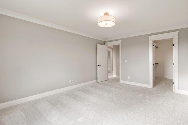 unfurnished bedroom with light colored carpet, ornamental molding, and a walk in closet