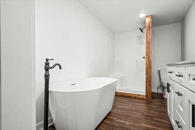 bathroom featuring hardwood / wood-style flooring, vanity, a bathing tub, and toilet