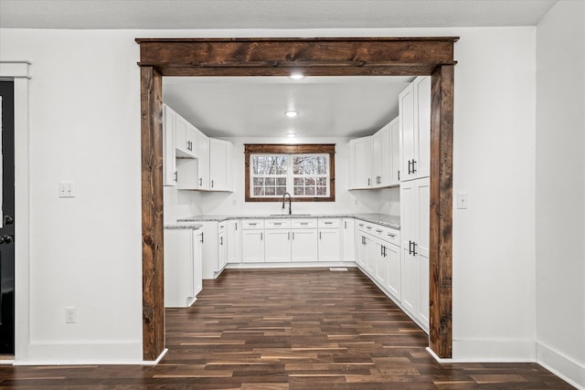 kitchen featuring white cabinetry, sink, light stone counters, and dark hardwood / wood-style floors