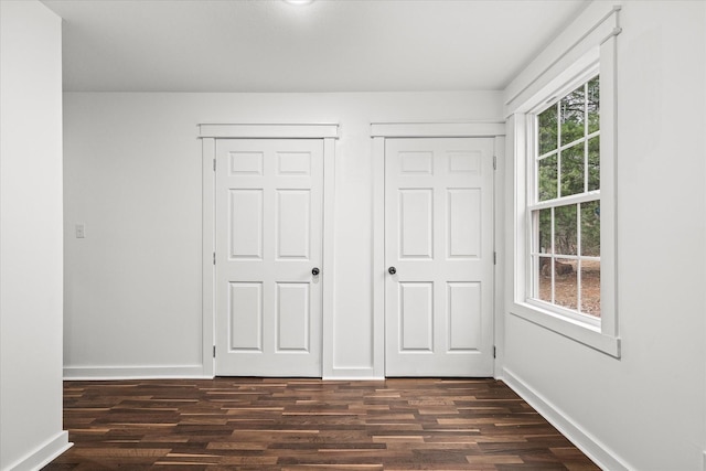 unfurnished bedroom featuring two closets and dark hardwood / wood-style flooring