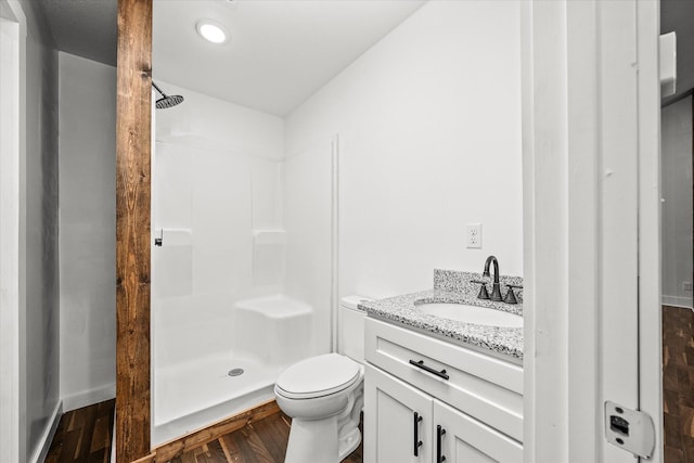 bathroom with a shower, hardwood / wood-style floors, vanity, and toilet