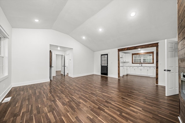 unfurnished living room with dark wood-type flooring, sink, and vaulted ceiling