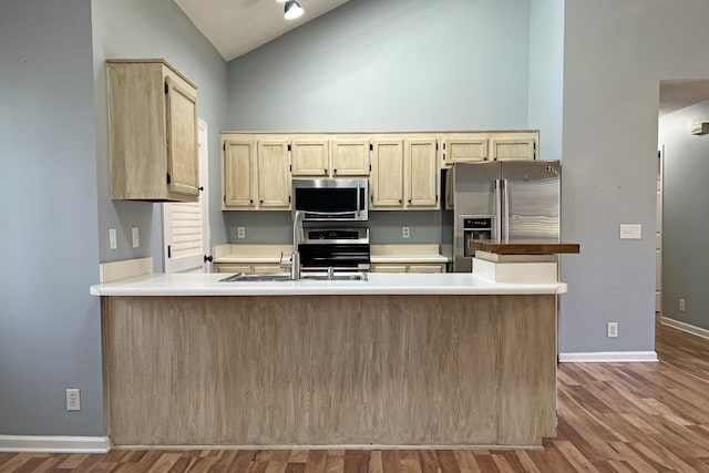 kitchen featuring hardwood / wood-style flooring, appliances with stainless steel finishes, high vaulted ceiling, and light brown cabinets