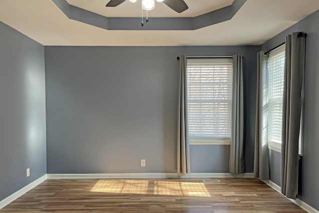 spare room featuring ceiling fan, a raised ceiling, and light hardwood / wood-style floors