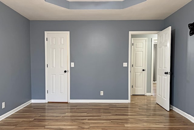 unfurnished bedroom with a raised ceiling and hardwood / wood-style floors