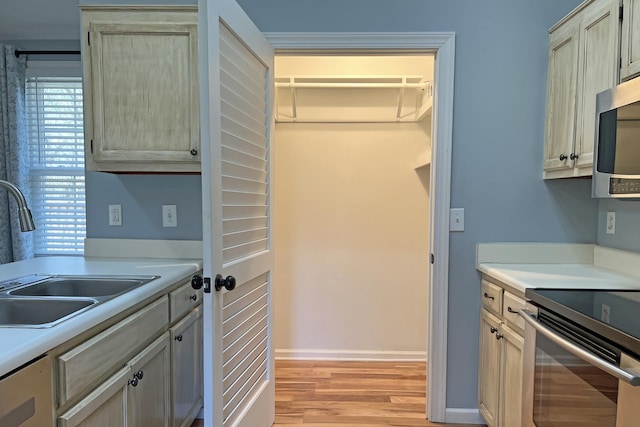 kitchen with appliances with stainless steel finishes, sink, and light hardwood / wood-style floors