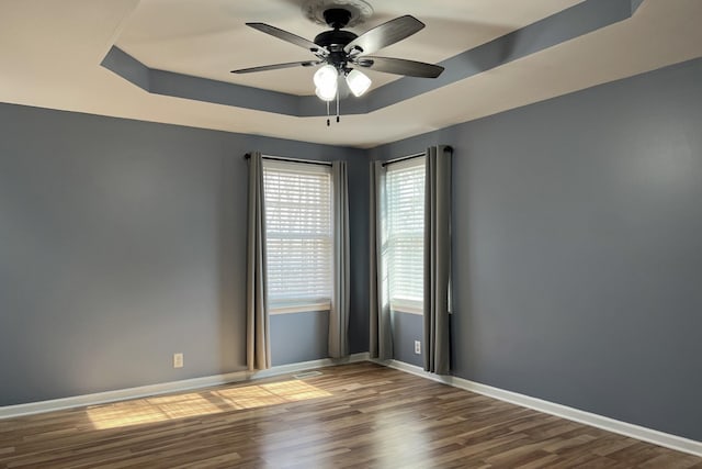 spare room with ceiling fan, a raised ceiling, and hardwood / wood-style floors